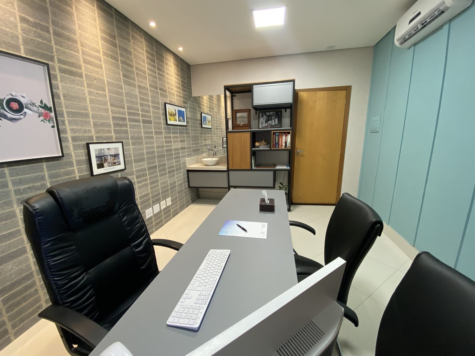 Consultório do IPEC, com mesa de atendimento e parede revestida em pedra