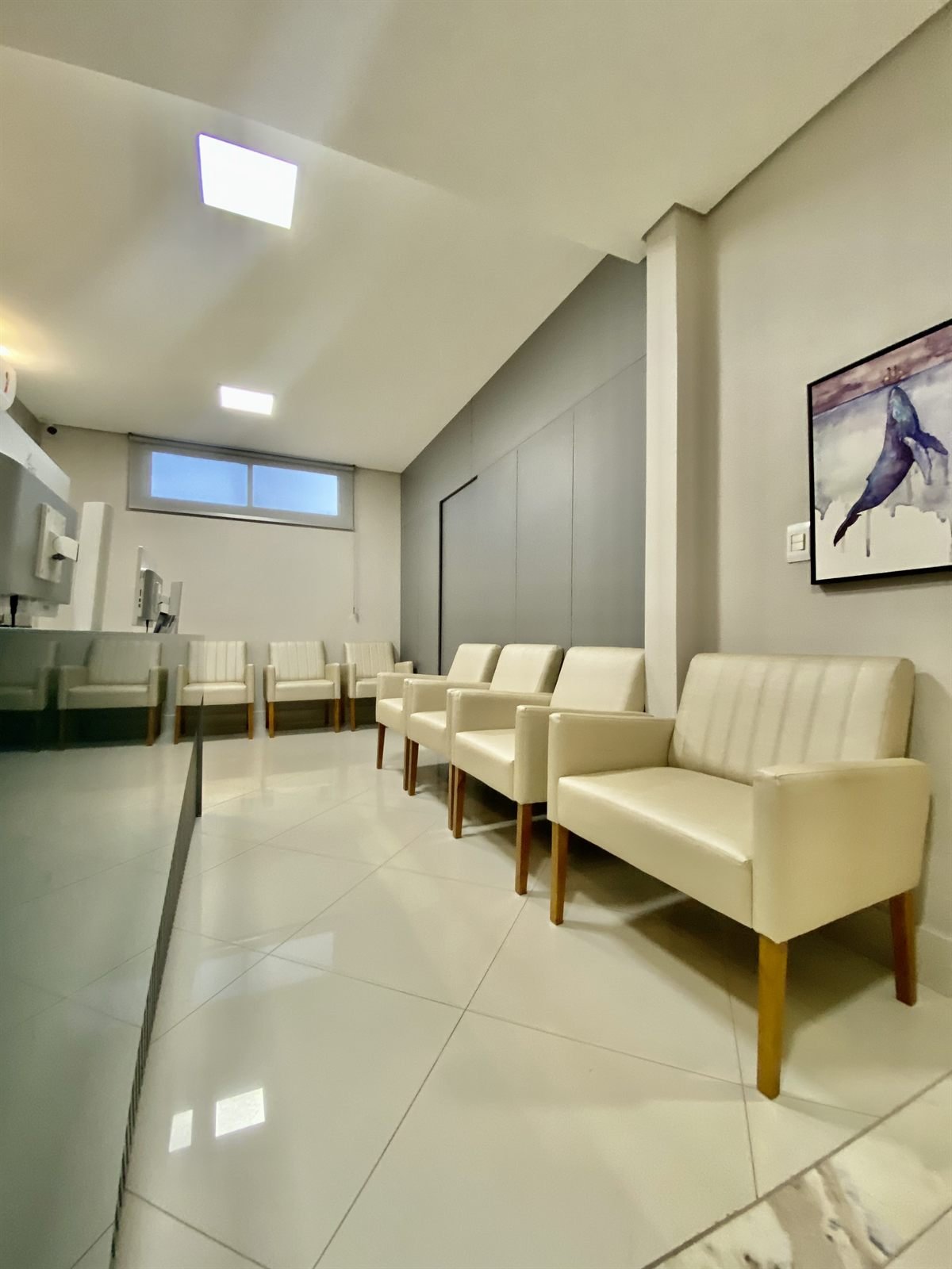 Sala de espera do IPEC, com poltronas claras e iluminação suave